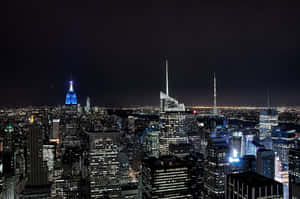 紐約市天際線的夜景，摩天大樓燈火通明，帝國大廈發出藍色光芒。