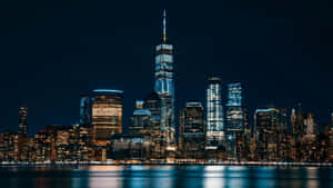 紐約市天際線的夜景，閃爍的摩天大樓和水面倒影。