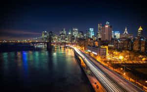 夜間城市景觀，建築物燈火通明，水上橋樑上車輛的光跡。