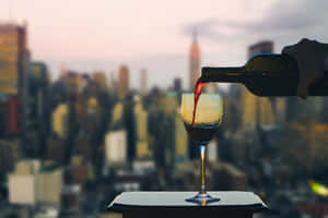 紅酒被倒入玻璃杯，背景是黃昏時分的城市天際線。 — 紐約市 壁紙