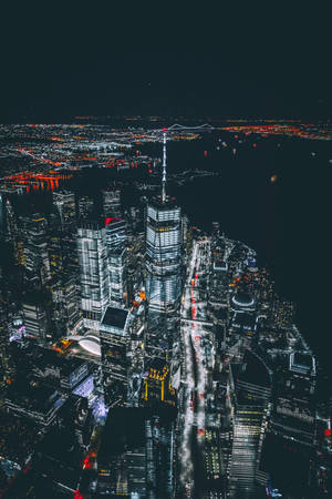 夜晚空中俯瞰密集的城市，明亮的燈光與河流