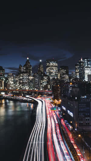 夜間城市景觀，沿河濱高速公路有流動的交通燈光。