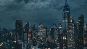 多雲天空下，紐約市天際線的夜景，摩天大樓燈火通明。 — 帝國大廈 壁紙