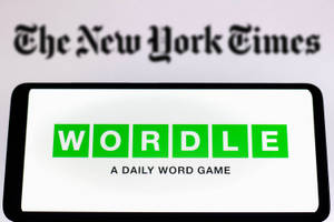 智能手機顯示Wordle遊戲標誌，背景係模糊嘅《紐約時報》。
