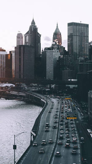 繁忙的高速公路橋，車輛在日落時分流向密集的城市天際線。 — 紐約市 壁紙