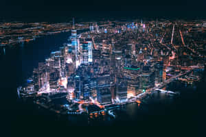 紐約市天際線的夜間鳥瞰圖，閃爍的建築物和黑暗的水面。