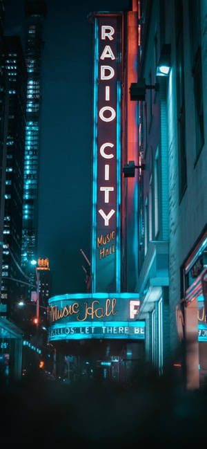 Radio City Music Hall 霓虹燈牌在夜晚的城市中發光。 — 紐約市 壁紙