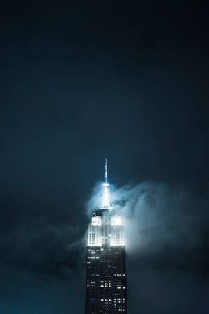 帝國大廈在夜間透過烏雲亮起