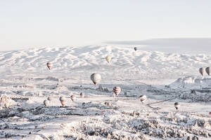 熱氣球漂浮在白雪覆蓋的山地地形上。 — 冬天 壁紙