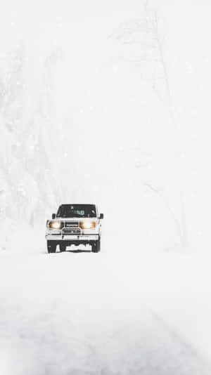 白色貨車在冬季森林的猛烈暴風雪中行駛。