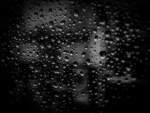 單色模糊背景下的玻璃上的雨滴。