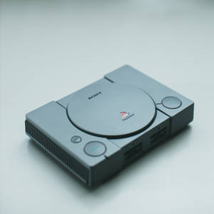 銀色 PlayStation 1 主機放在白色表面上，光線柔和。 — PlayStation GIF 壁紙