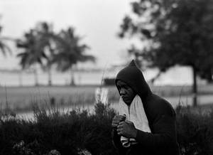 穿著連帽衫的男人在棕櫚樹和灌木叢附近的戶外拿著毛巾。 — 跑步 壁紙