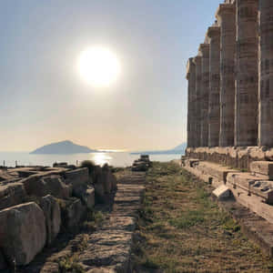 海邊的古廟遺跡，陽光灑在水面上，遠處有島嶼。 — 太陽 壁紙