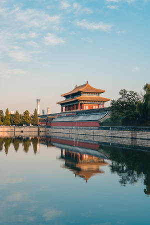 古代中式宮殿大門倒映在清澈天空下的靜水中。