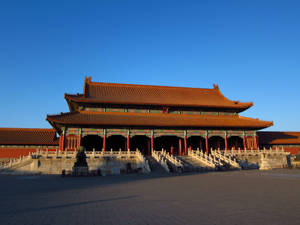 令人印象深刻的中國古代宮殿，橙色屋頂和紅色柱子沐浴在金色的夕陽中。