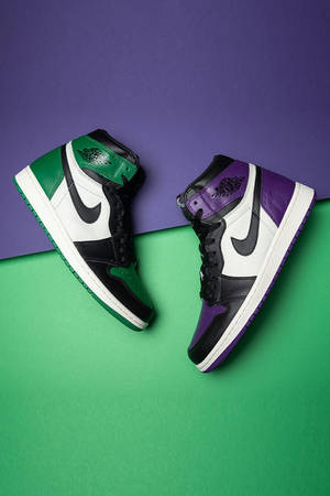 兩雙顏色分塊的 Air Jordan 運動鞋，背景為綠色和紫色。