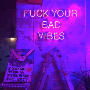 寫著「FUCK YOUR BAD VIBES」的霓虹燈牌，在磚牆上，旁邊有梯子和一張握手海報。