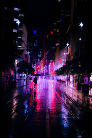 夜晚在霓虹燈下，一個人在濕漉漉的城市街道上獨自行走。