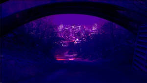 夜晚透過石拱門看到的發光城市，帶有紫色燈光。 — 深紫色美學 GIF 壁紙