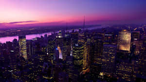 紐約市天際線在黃昏時，閃爍的建築物和紫色的天空。