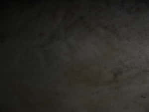 帶有污漬和裂縫的深色紋理混凝土牆。