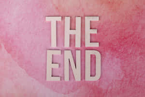 粉紅色水彩背景上拼出「THE END」的木製字母。