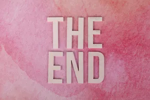 粉紅色水彩背景上拼出「THE END」的木製字母。