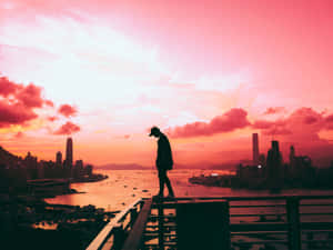 人站在天台欄杆上觀看城市日落 — 天際線 壁紙