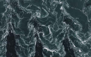從上方看到的深綠色洶湧海浪與白色泡沫旋轉。