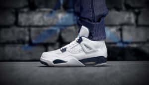 一雙白色和海軍藍色的Air Jordan 4運動鞋在塗鴉磚牆上的特寫。