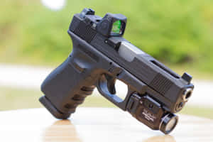 黑色手槍配紅點瞄準器和戰術燈在木質表面上。 — 槍 壁紙