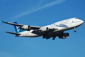 紐西蘭航空波音747飛機喺藍天背景下放下起落架下降。