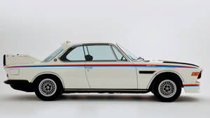 帶有藍色、紅色和黑色條紋的白色BMW 3.0 CSL賽車在攝影棚
