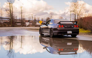 黑色跑車在濕漉漉的道路上的水坑中反射，黃昏時分。 — 日產 Skyline GTR R33 壁紙