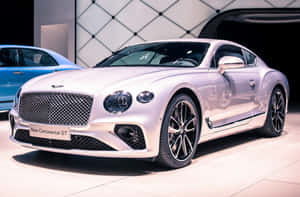 銀色賓利 Continental GT 在車展上展出，後面有一輛藍色汽車。