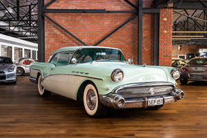 復古薄荷綠色1957年Buick Roadmaster，帶有鍍鉻細節，陳列在磚牆的汽車展廳中。 — 汽車 壁紙
