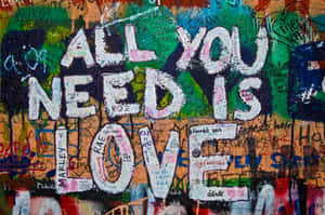 塗鴉牆，在彩色標籤上用白色油漆寫著「All You Need Is Love」。