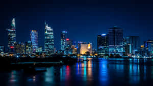 夜晚城市景觀，發光的摩天大樓倒映在河流中。
