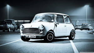 一輛白色經典Mini Cooper在夜間停車場停泊在街燈下。