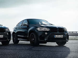 兩輛黑色BMW SUV停泊在鋪砌路面上，天空多雲。 — 寶馬X6 M 壁紙