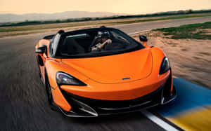 橙色McLaren跑車在日落時分在沙漠賽道上疾馳。