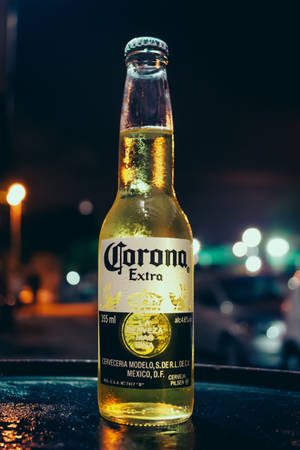 夜晚濕桌上冰凍的Corona啤酒瓶，背景是模糊的城市燈光。