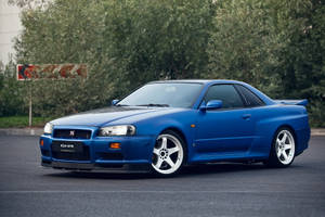 藍色日產R34 GTR跑車停在瀝青路上，靠近樹木。 — 藍色 壁紙