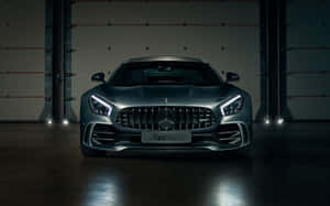 一輛啞光灰色 Mercedes-AMG GT 跑車在黑暗的工業車庫中被聚光燈照亮。