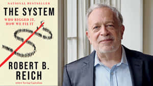 Robert B Reich身穿西裝，站在他的書本封面旁，書名為The System。 — 書籍 壁紙