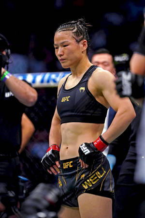 身穿UFC裝備的女性MMA拳手在比賽後站在八角籠中。