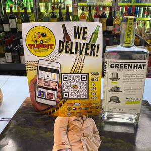 酒舖櫃枱展示了一個送貨廣告和一瓶帶有風衣倒影的氈酒。