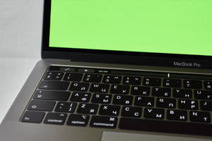 銀色 MacBook Pro，配備西里爾字母鍵盤及顯示計時器的綠色屏幕。