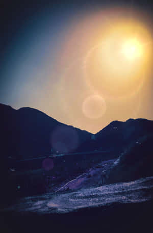 一個人在山路上行走，太陽在山峰後落下，伴隨著鏡頭光暈。